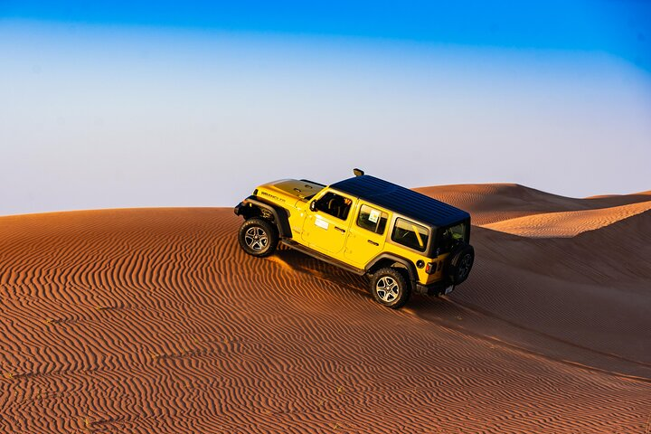 Experience the rugged beauty of the Dubai desert with a self-driving Jeep Wrangler. Navigate stunning dunes while enjoying guided support and refreshing water as you embark on this unforgettable journey.